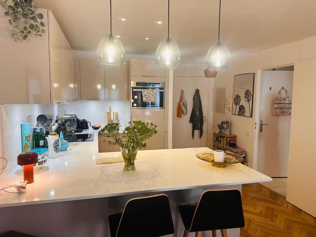 une cuisine avec un îlot avec des chaises et des lumières dans l'établissement Lovely one bedroom apartment with balcony & wifi just minutes walk from Palais and Cannes beaches 109, à Cannes