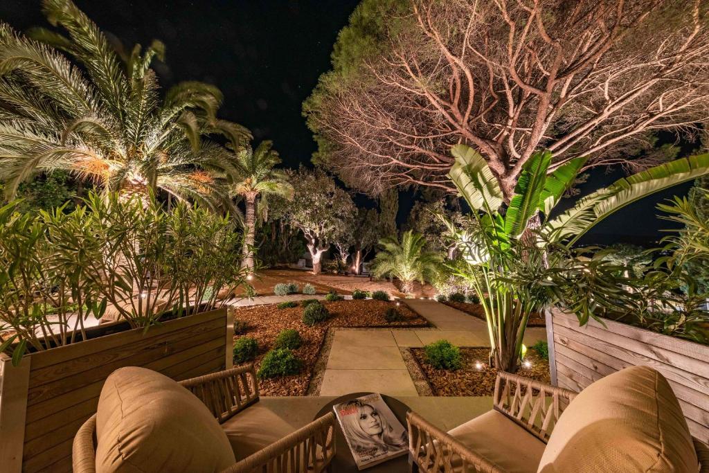 a garden at night with palm trees and a bridge at Les Capucines Saint Tropez in Saint-Tropez