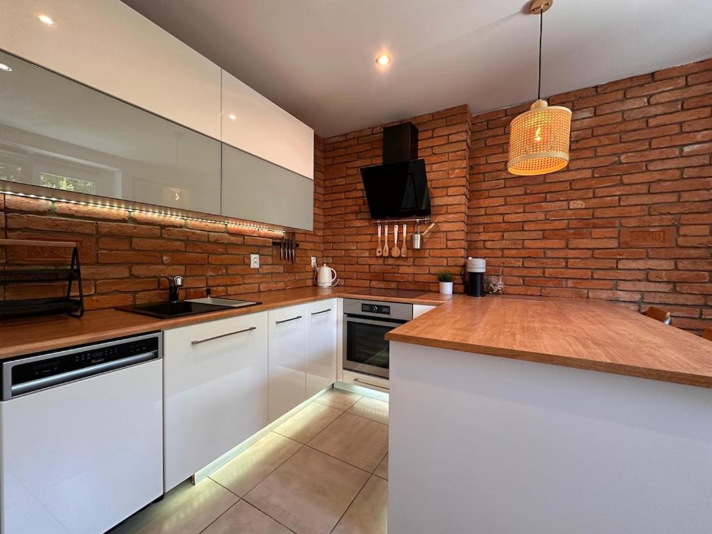 a kitchen with white cabinets and a brick wall at Haban Haus in Bratislava