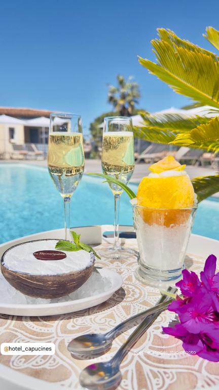 a table with wine glasses and a plate of food at Les Capucines Saint Tropez in Saint-Tropez
