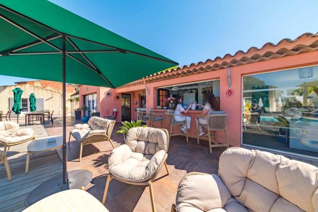 a patio with white chairs and a green umbrella at Les Capucines Saint Tropez in Saint-Tropez