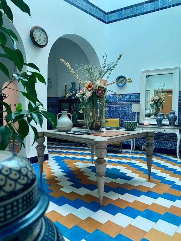 a room with a table with a vase of flowers on it at Hostal Casa Alborada in Conil de la Frontera