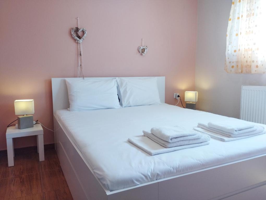 Una cama blanca con toallas encima. en Dimi apartment, en Nea Peramos