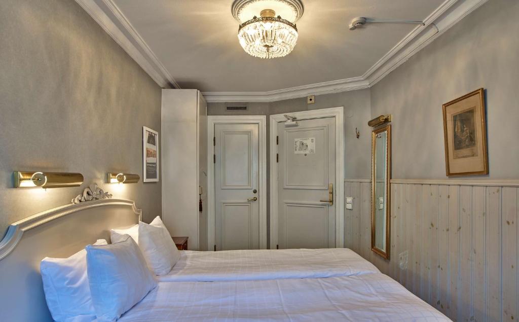 a bedroom with a large white bed with a chandelier at Scandic Gamla Stan in Stockholm