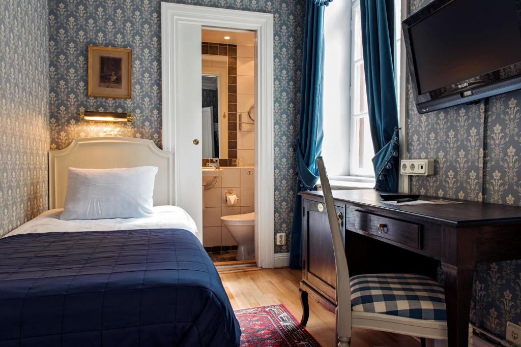 a bedroom with a bed and a desk with a television at Scandic Gamla Stan in Stockholm
