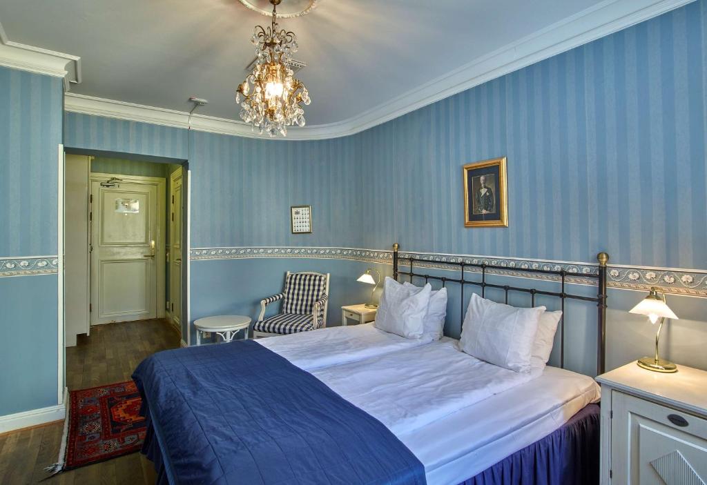 a bedroom with a bed with blue walls and a chandelier at Scandic Gamla Stan in Stockholm