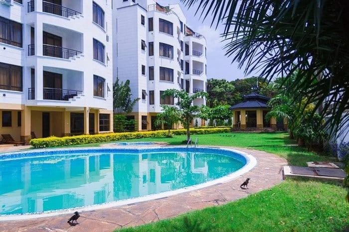 a large swimming pool in front of a building at Impala Suites in Mombasa