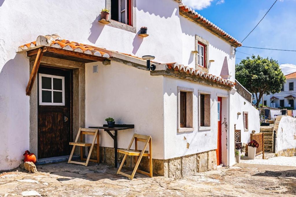 une petite maison blanche avec des tabourets à l'extérieur dans l'établissement Private, romantic and cozy Room in Azenhas do Mar, à Colares