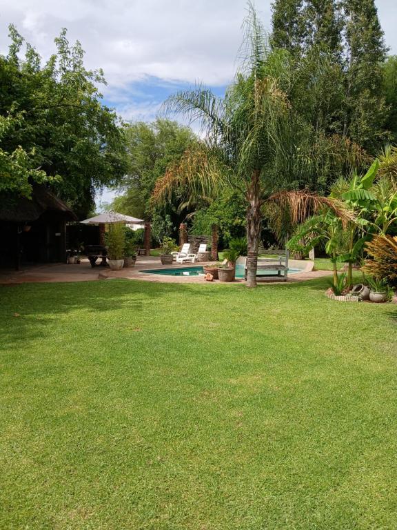 un patio con un parque con un banco y un árbol en Karoo 2, en Douglas