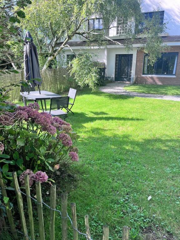 un jardin avec une table et un parasol dans une cour dans l'établissement Gîte de la Biscuiterie, à Cucq