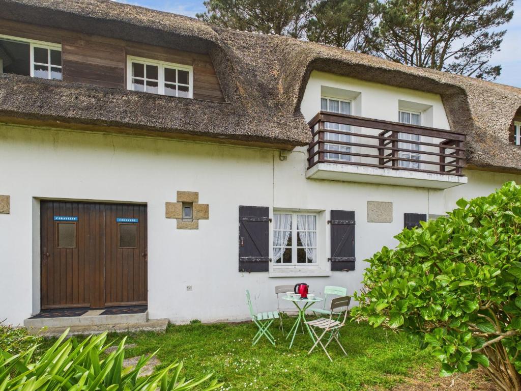 Ce cottage dispose d'un toit de chaume, d'une table et de chaises. dans l'établissement La Corvette - Pour 4 dans une chaumière avec jardin, au Guilvinec