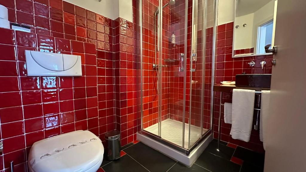 a red tiled bathroom with a toilet and a shower at Hostal Casa Alborada in Conil de la Frontera
