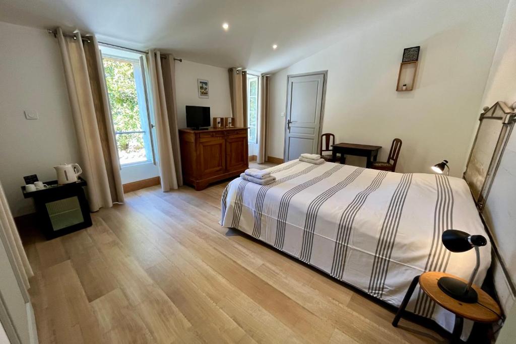 een slaapkamer met een bed en een houten vloer bij L'Hermione - Room in the heart of St Martin de Ré in Saint-Martin-de-Ré