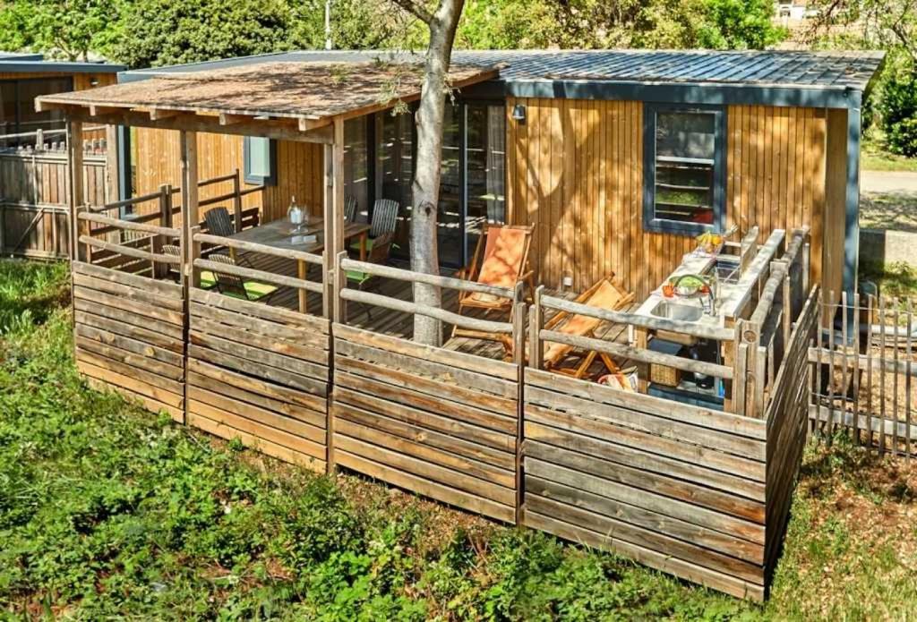 une cabane en bois avec clôture dans l'herbe dans l'établissement Chalet 4 étoiles - efaaba, à Roquebrune-sur Argens