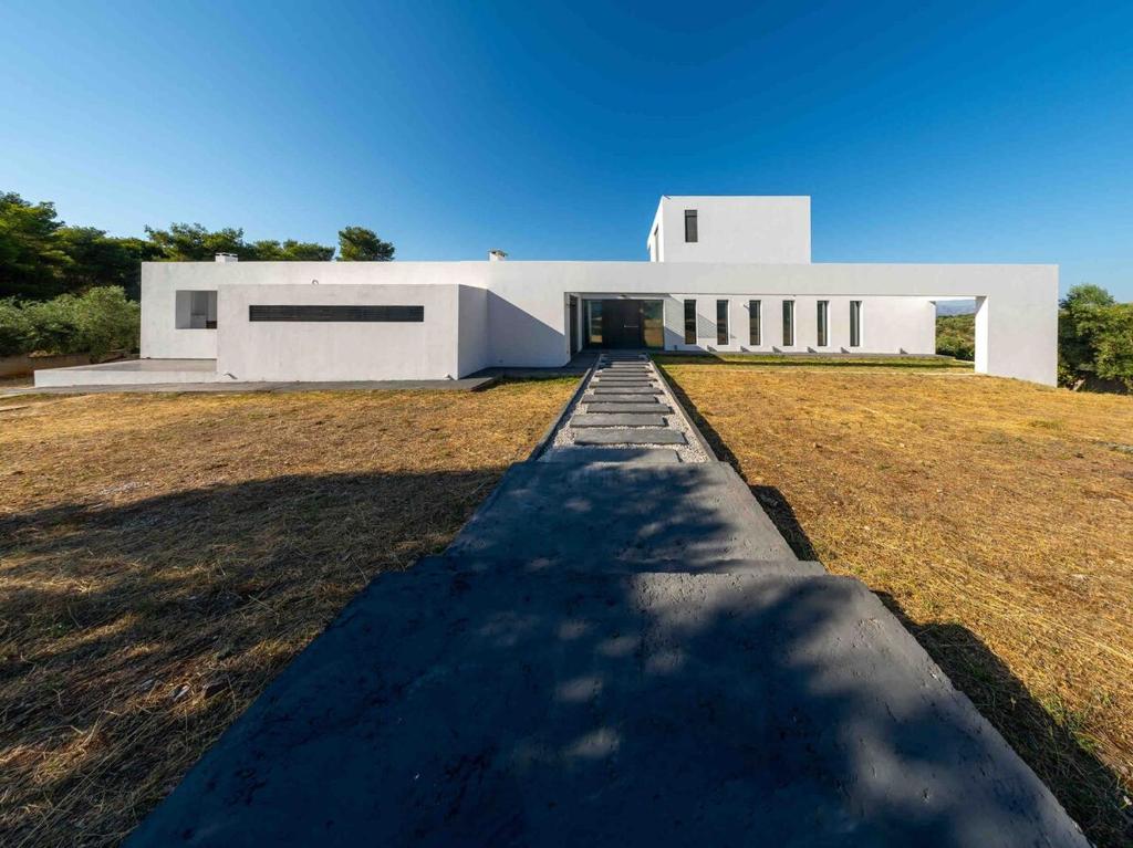 a white building with a pathway leading to it at Villa Scorpios with private pool in Áyioi Apóstoloi