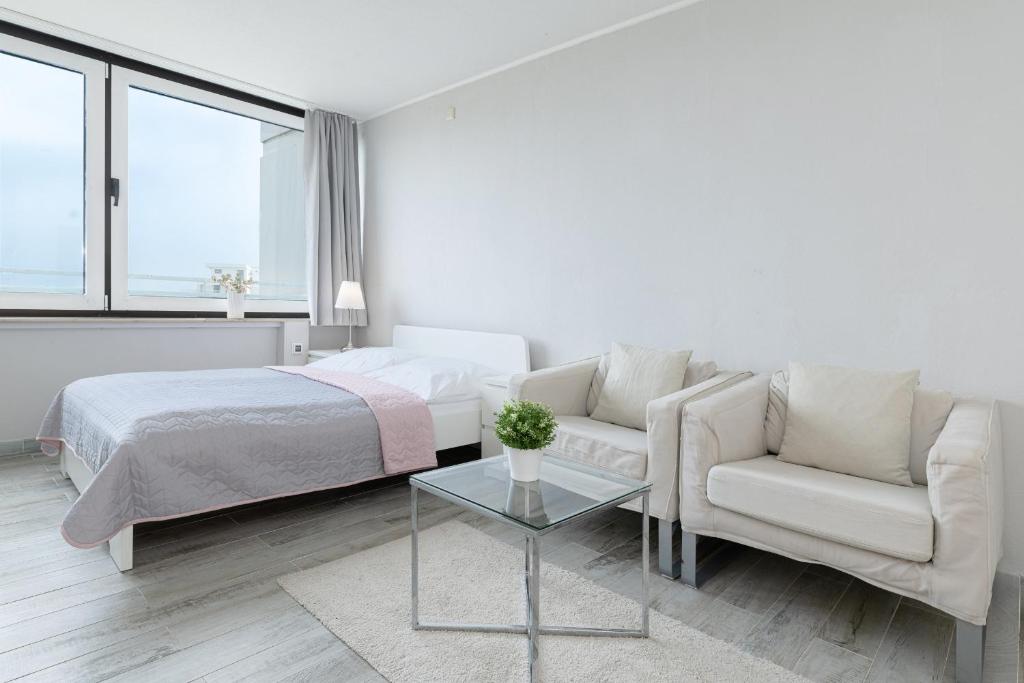 a white bedroom with a bed and a couch and a table at Marina Wendtorf Kajüte in Wendtorf