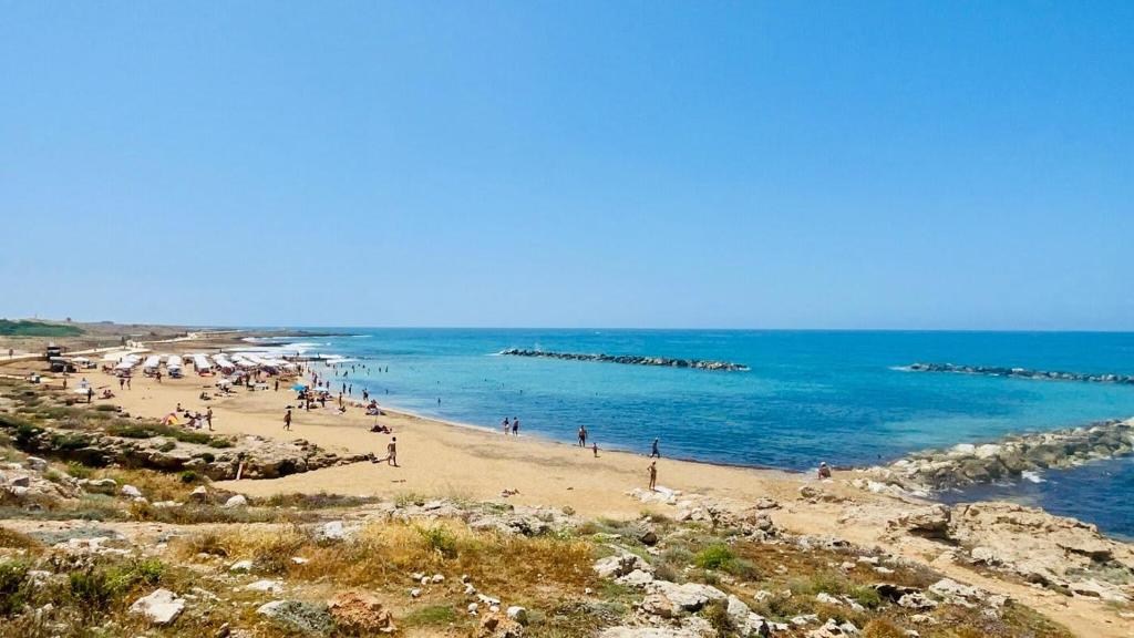 un grupo de personas en una playa cerca del océano en Elegant beachside apt - 1 min walk to Venus beach, en Paphos