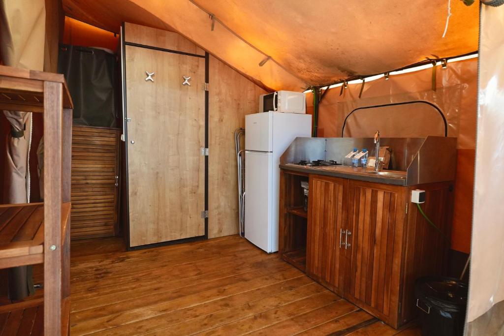 a kitchen with a white refrigerator and a wooden floor at Camping 3 Estrellas in Gavà