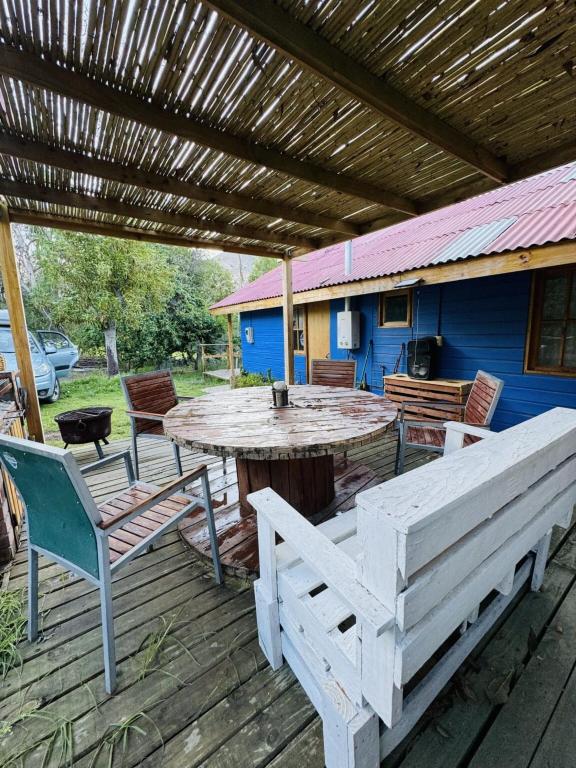 a wooden table and chairs on a deck with a wooden roof at Cabaña de Campo tulahuen in Piedra Lisa