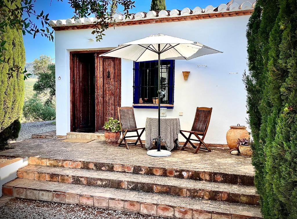 a table and chairs with an umbrella in front of a house at Romantisches Apartment, Finca nahe Malaga in Ríogordo