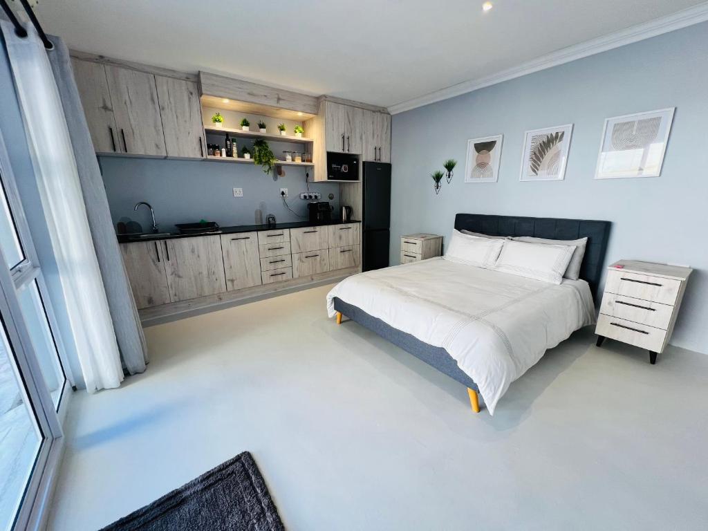 a bedroom with a large bed and a kitchen at Rissie's Place in Gordonʼs Bay