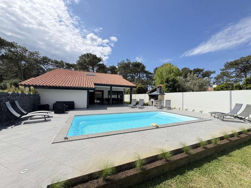 une piscine devant une maison dans l'établissement Villa d'exception avec piscine chauffée proche océan à Biscarrosse Plage - FR-1-831-8, à Biscarrosse
