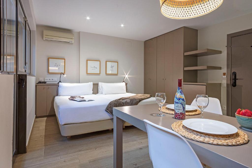 Una habitación de hotel con una cama y una mesa con copas de vino. en Aparthotel Bcn Montjuic, en Barcelona