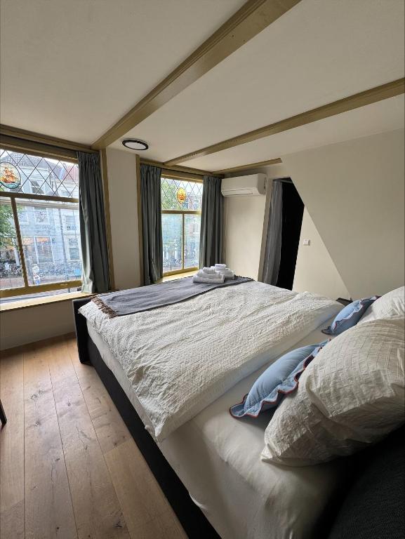 a bedroom with a large bed and two windows at The Hazel House in Haarlem