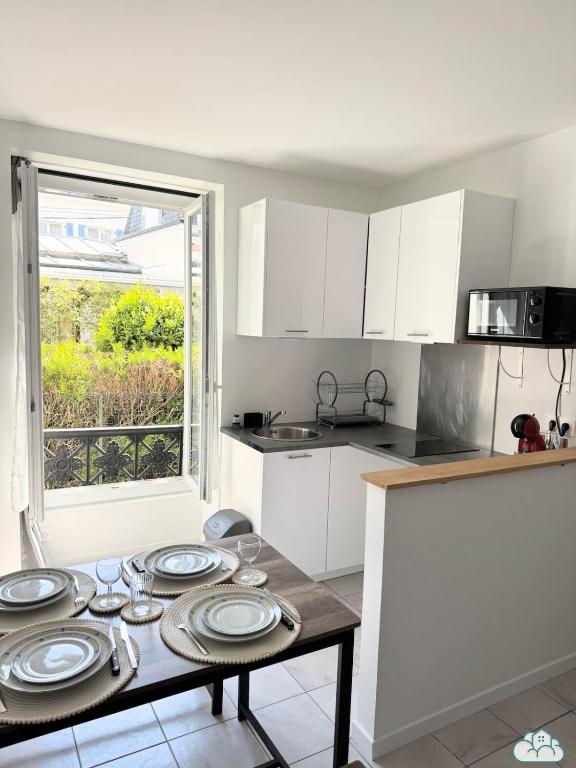 une cuisine avec une table avec des assiettes dessus dans l'établissement Au Fil de la Marne à 15mn Disney et 25mn Paris, à Lagny-sur-Marne