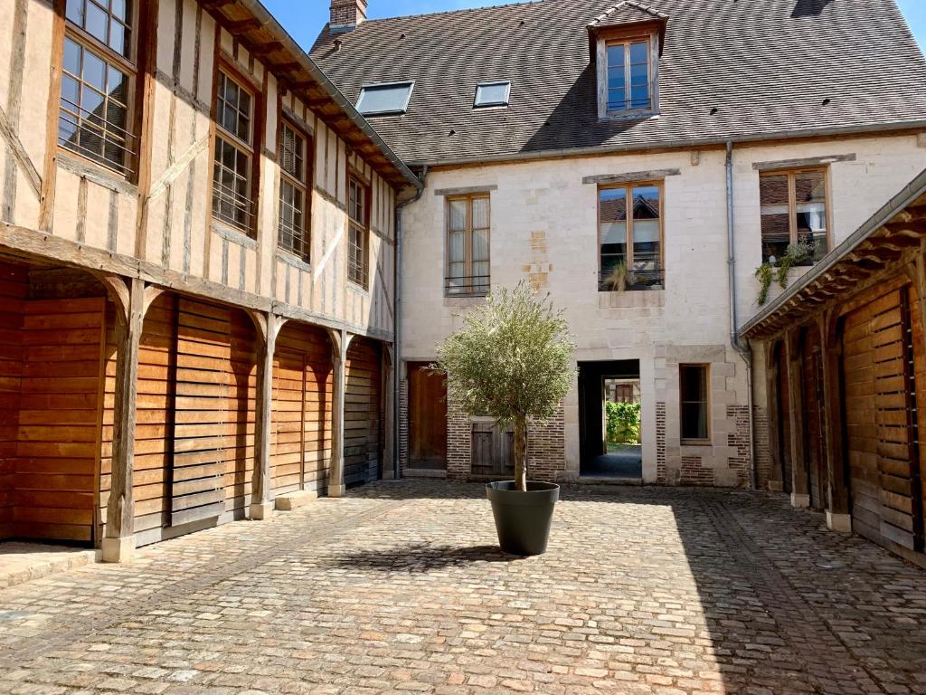 une cour d'un bâtiment avec un arbre dans un pot dans l'établissement Au coeur de Troyes, Atelier de la Cathédrale, à Troyes