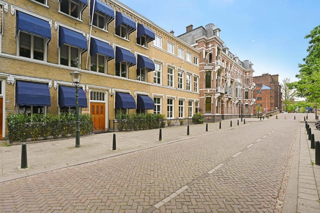 a cobblestone street in front of buildings with blue awnings at novallure nassau residence in The Hague