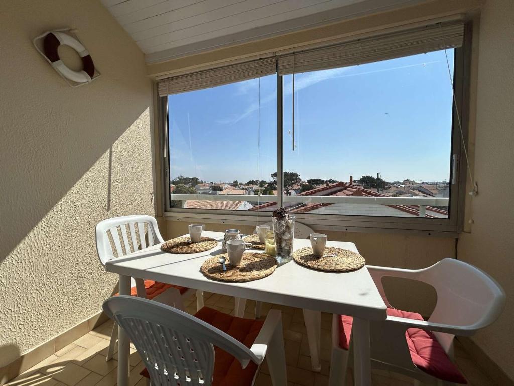 une table blanche avec des chaises et une fenêtre avec vue dans l'établissement Studio avec Mezzanine, Balcon et Garage à 200m de la Plage – 4 Couchages - FR-1-224-247, à Saint-Hilaire-de-Riez