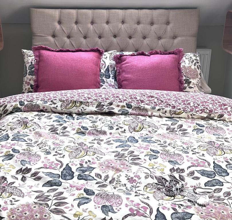 ein Bett mit rosa und lila Kissen darauf in der Unterkunft Bath Central Free Parking One Double Ensuite Room in Historical Mews Cottage in Bath