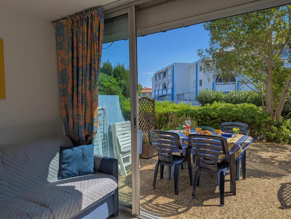 d'une terrasse avec une table, des chaises et une porte en verre. dans l'établissement Sol-y-Days Floralies, Studio grande terrasse résidence avec piscine, au Grau-du-Roi