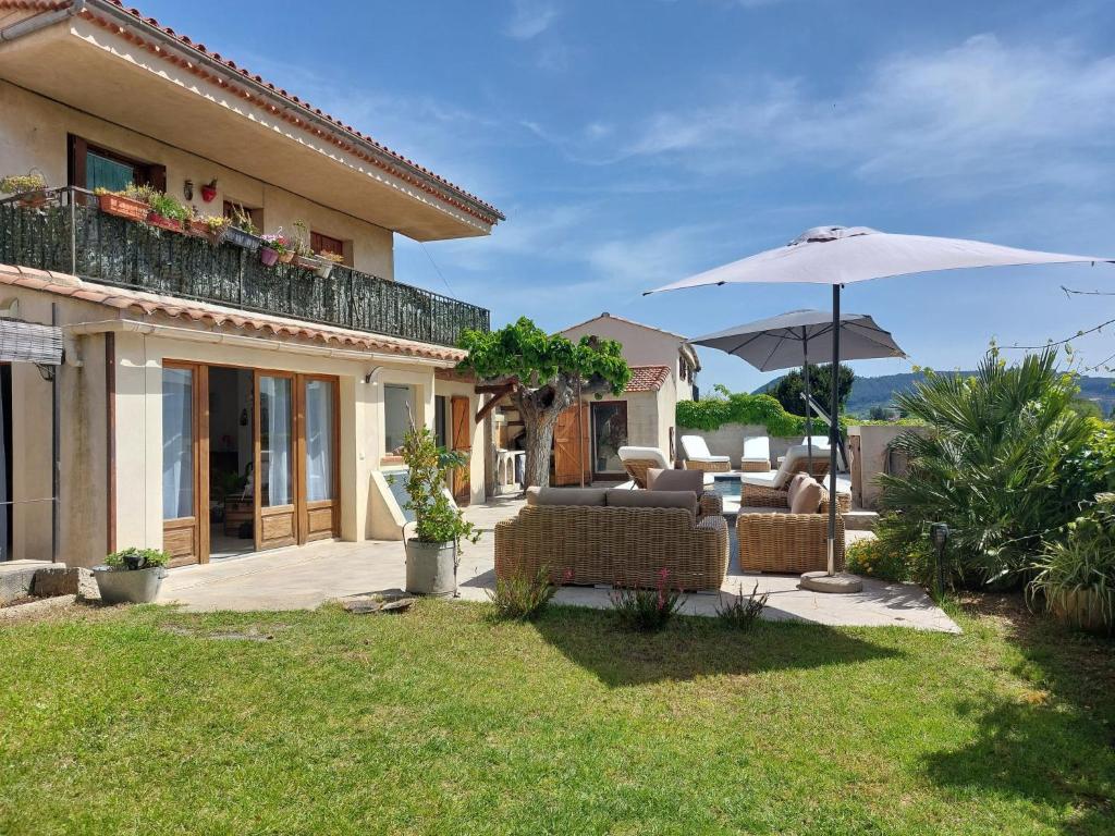 Cette maison dispose d'une terrasse avec des chaises et un parasol. dans l'établissement Apartment La Bastide Neuve by Interhome, à Saint-Cyr-sur-Mer