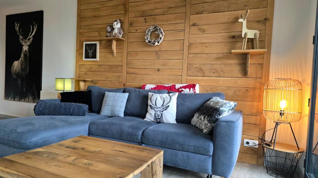 un sofá azul en una sala de estar con una pared de madera en Le Caribou La Mongie, en Bagnères-de-Bigorre