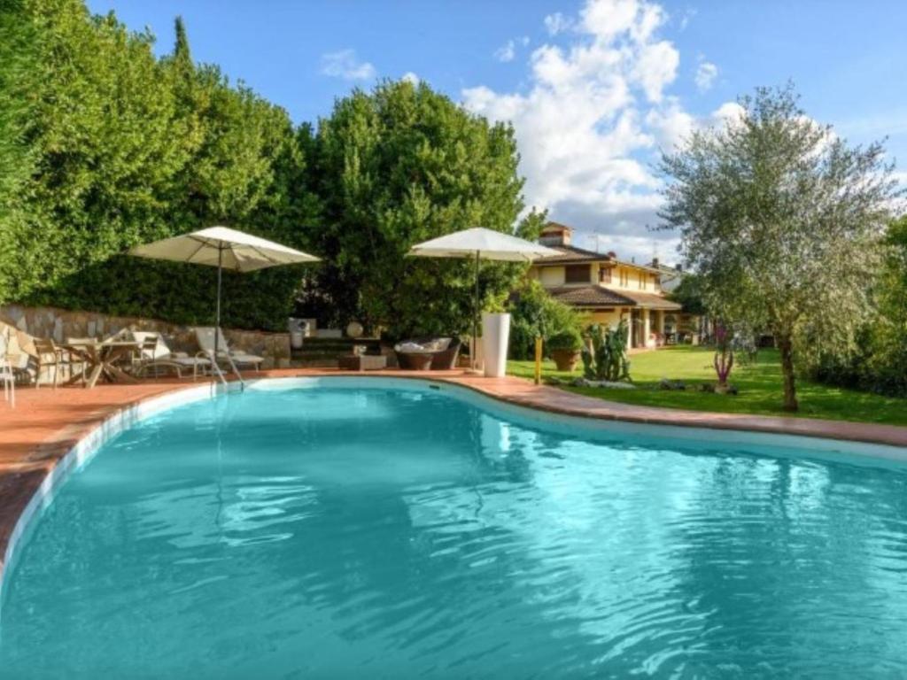 una piscina con ombrelloni e una casa di Villa Villa Il Guscio by Interhome a Terranuova Bracciolini