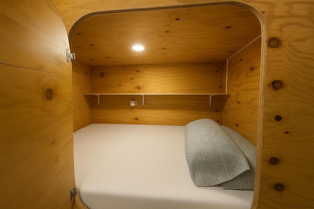 Una pequeña habitación con una cama blanca en una cabaña de madera. en Cubik Rooms, en Madrid