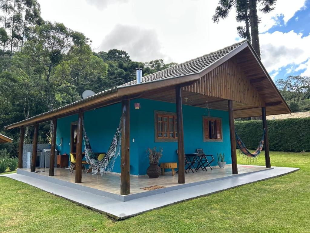Una casa azul con una gran terraza con hamacas. en Chale Sitio Esperança, en Sapucaí-Mirim