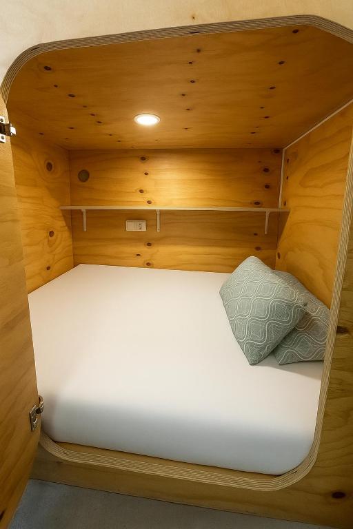 a small bed in a wooden cabin with a pillow at Cubik Rooms in Madrid