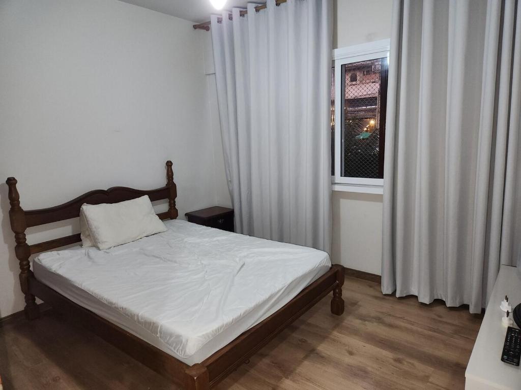 a bedroom with a bed and a window with white curtains at Comodidade ao lado da ESALQ USP in Piracicaba
