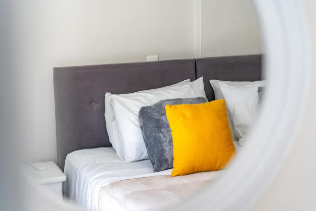 a bed with a yellow pillow and white pillows at Donna's luxury home in Kassiopi 300m from the sea in Kassiopi