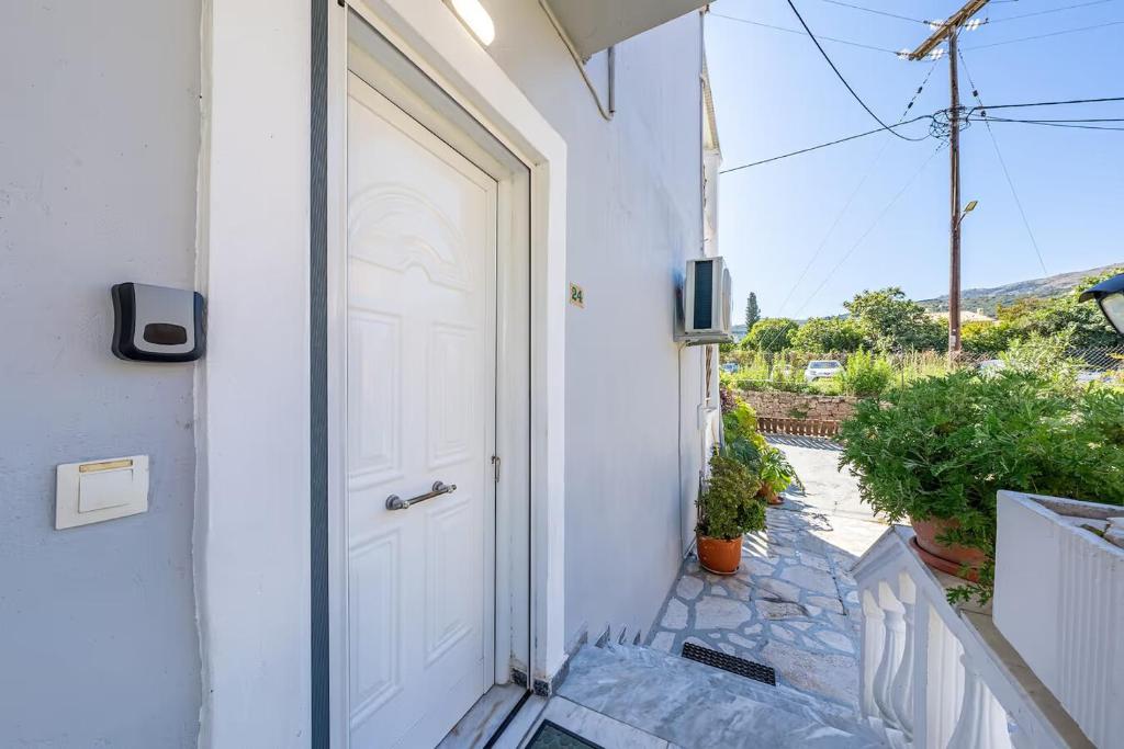 a white door on a white house with a porch at Donna's luxury home in Kassiopi 300m from the sea in Kassiopi