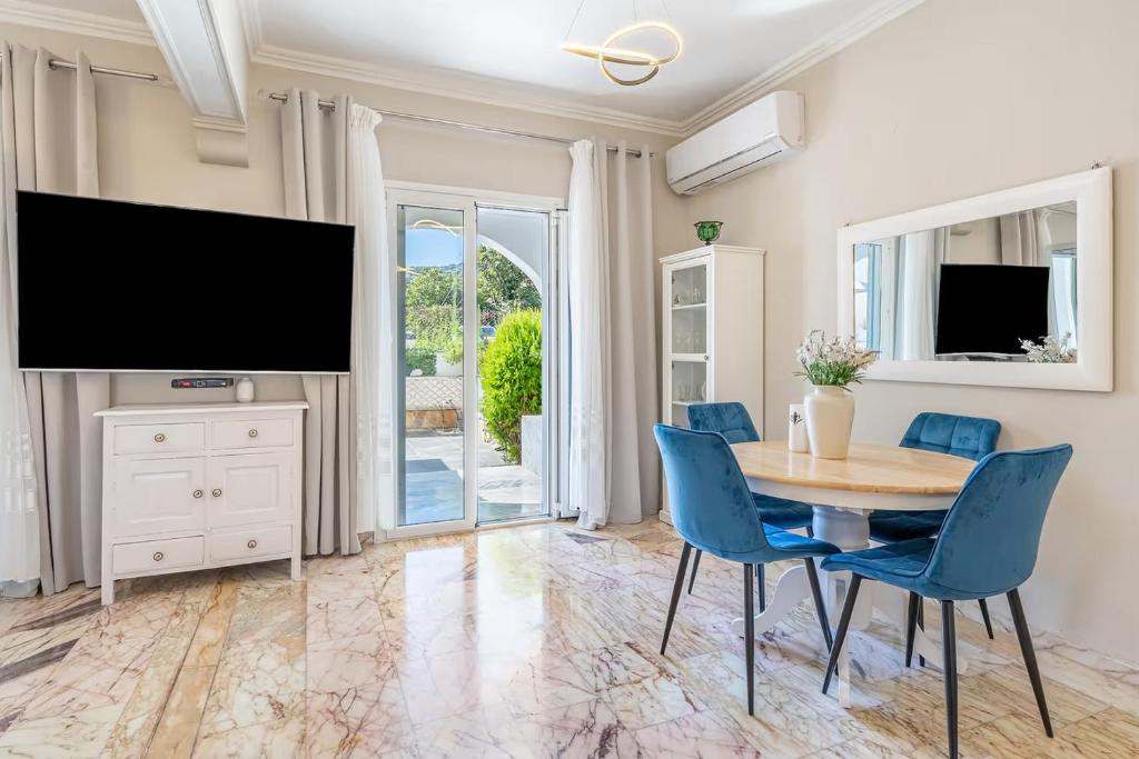 a dining room with a table and chairs and a flat screen tv at Donna's luxury home in Kassiopi 300m from the sea in Kassiopi