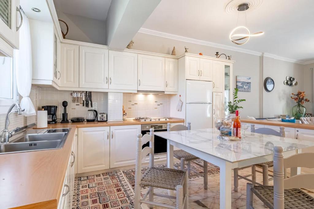 a kitchen with white cabinets and a table with chairs at Donna's luxury home in Kassiopi 300m from the sea in Kassiopi