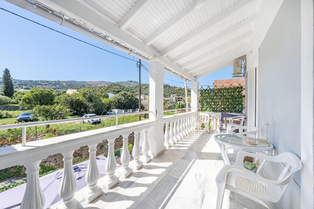 a white balcony with a table and white chairs at Donna's luxury home in Kassiopi 300m from the sea in Kassiopi