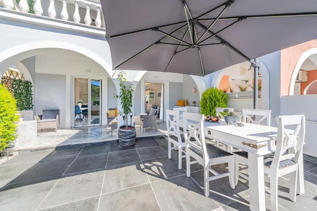 a dining room with a white table and chairs and an umbrella at Donna's luxury home in Kassiopi 300m from the sea in Kassiopi