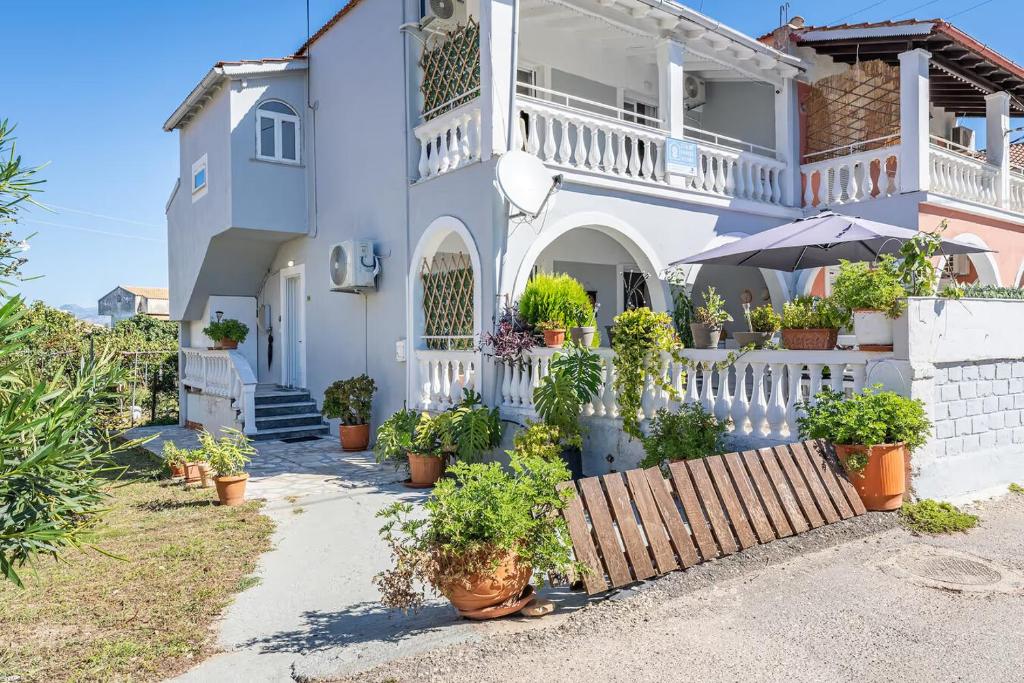 a white house with potted plants in front of it at Donna's luxury home in Kassiopi 300m from the sea in Kassiopi