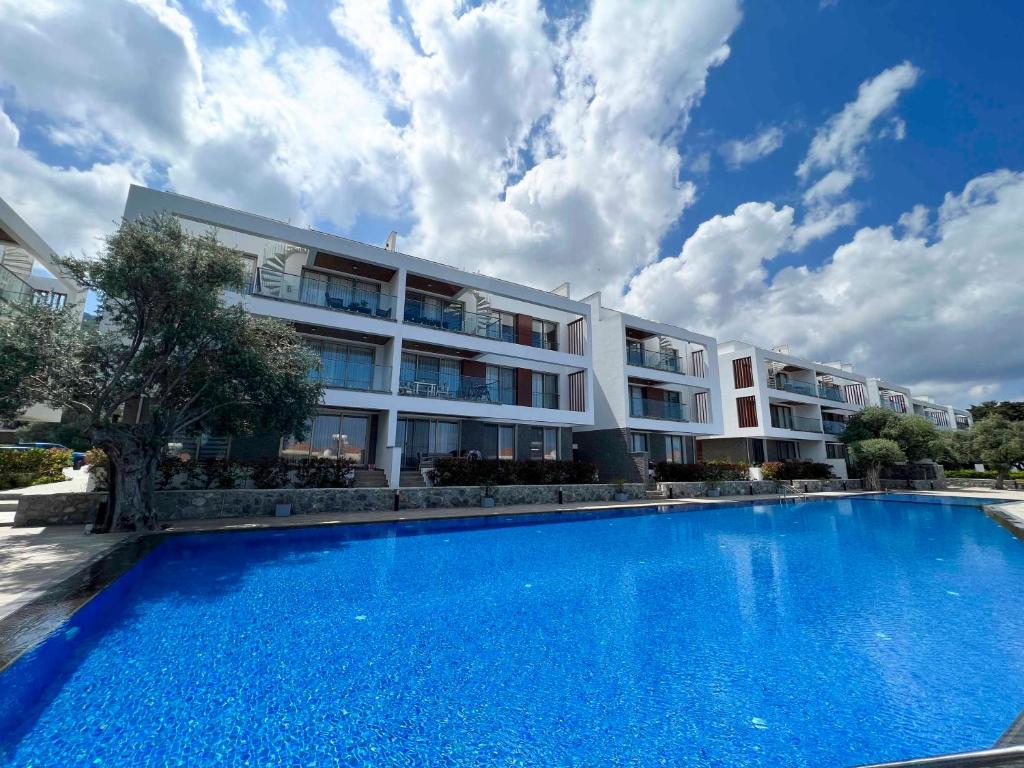 a large apartment building with a large blue swimming pool at Olive Hill 14 Cozy 2-Bed Garden Apt by HolidayKeys in Kérynia