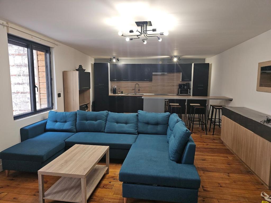 Una sala de estar con un sofá azul y una mesa. en Le REFUGE DIEPPOIS plein centre ville BY HOLIDIEPPE, en Dieppe